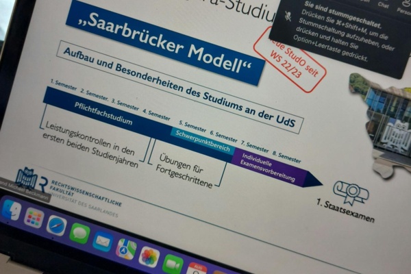 Laptopbildschirm mit geöffneter MS-Teams Veranstaltung. Gezeigt werden geteilte Folien, hier zum Jurastudium in Saarbrücken. Die konkrete Folie beschreibt den Aufbau des "Saarbrücker Modells" des Jurastudiums.